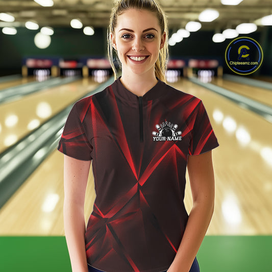 Woman wearing a red and black bowling shirt with a logo in a bowling alley.