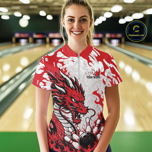 Person wearing a red and white dragon-themed bowling shirt in a bowling alley.