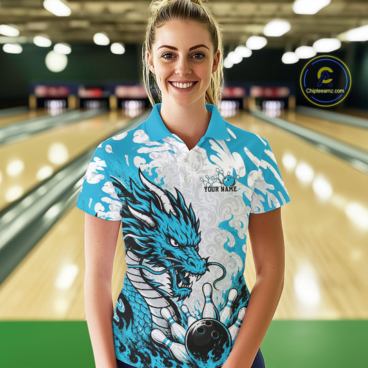 Woman wearing a blue and white bowling shirt with a dragon design in a bowling alley.