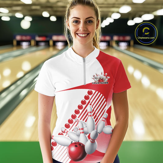 Female model wearing a white and red bowling quarter zip with flowing geometric stripes and dynamic bowling strike artwork inside a bowling alley.