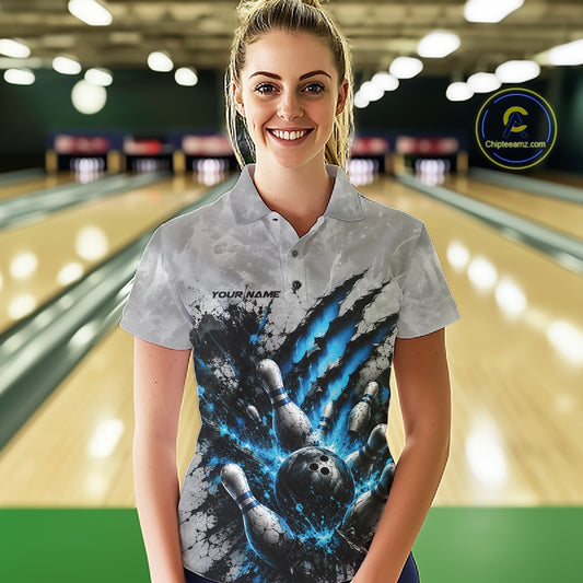 Front view of a female model wearing a gray bowling polo shirt featuring a dramatic blue bowling ball and pins graphic with claw-mark artwork in a bowling lane.