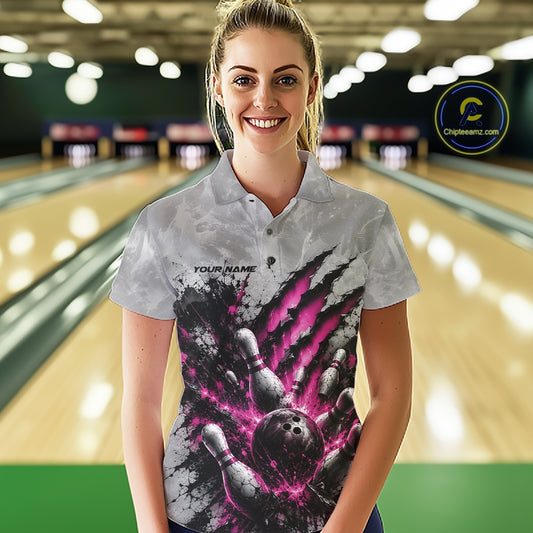 Front view of a female model wearing a gray bowling polo shirt featuring a dramatic pink bowling ball and pins graphic with claw-mark artwork in a bowling lane.