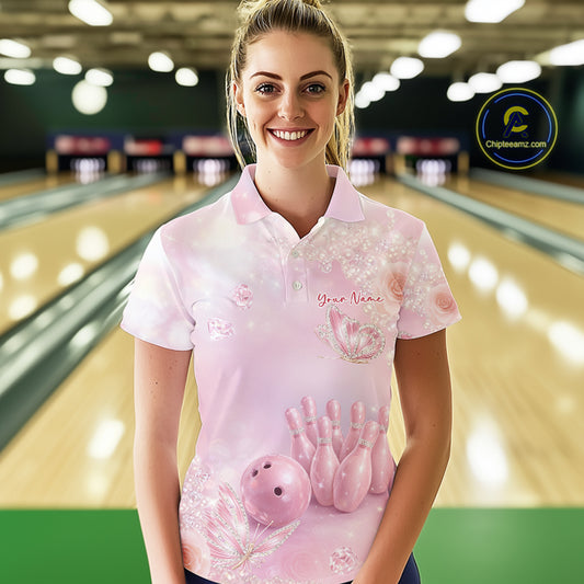 Female model wearing a bowling polo shirt in a bowling center with sparkling butterfly motifs, diamonds, bowling pins, and bowling ball graphics.