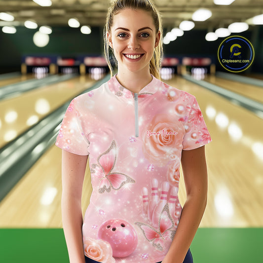 Female model at a bowling lane wearing a quarter-zip bowling shirt with sparkling butterfly motifs, diamonds, bowling pins, and a bowling ball design.