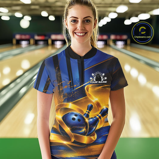 Front view of a female model wearing a bowling quarter zip shirt featuring a glossy blue bowling ball and pins wrapped in flowing gold ribbon accents at a bowling lane.