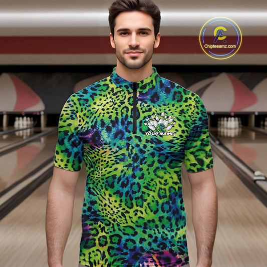 Man in a bowling alley wearing a blue, green, and black leopard-print bowling quarter zip shirt with “Your Name” and a bowling pins graphic on the chest.
