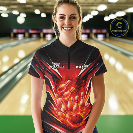 Front view female model in bowling lane wearing black and red quarter zip shirt showing flaming bowling ball striking pins with intense fire illustration.
