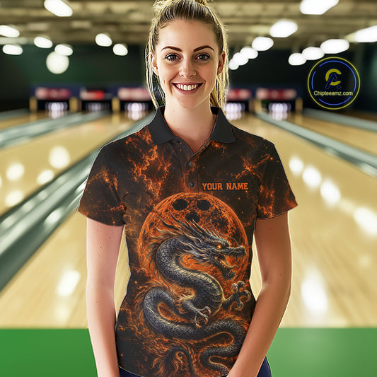 Front view of a female model in a bowling alley wearing an orange custom bowling polo shirt featuring an ancient dragon, flames, and a moon-inspired bowling ball design.
