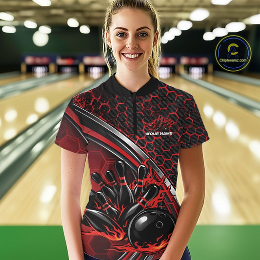 Front view of a female model wearing a black and red bowling quarter zip featuring honeycomb graphics and a flaming bowling strike motif in a bowling venue.