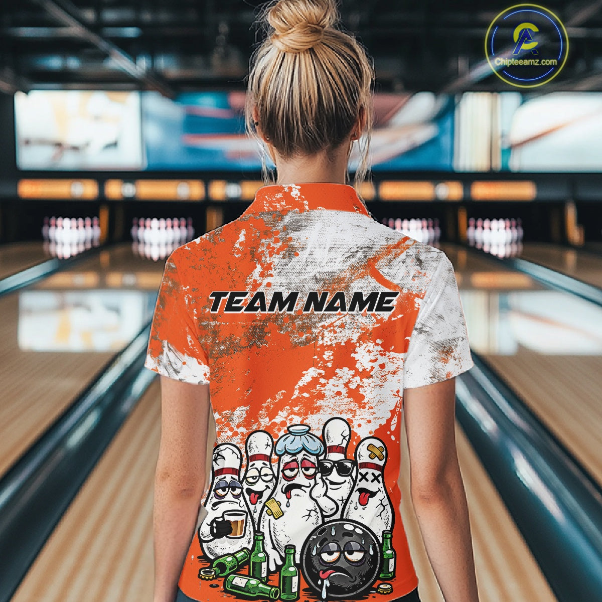 Back view female model at bowling lane wearing white polo with orange and white grunge splatter, cartoon bowling pins and bowling ball surrounded by beer bottles