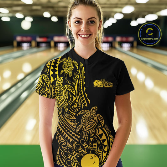 Female model wearing a black and gold bowling quarter-zip shirt at the lane with turtle pattern bowling artwork.