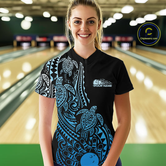 Female model wearing a black and blue bowling quarter-zip shirt at the bowling lane with tribal swirl accents and bowling artwork.