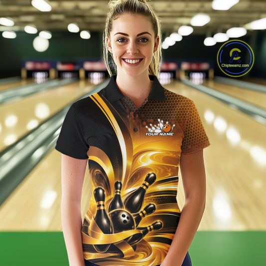 Front view of a female model inside a bowling center wearing a bowling polo shirt with glossy gold and black bowling ball and pins artwork.