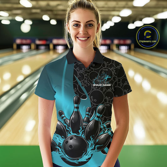 Front view of a female model in a bowling lane wearing a black and blue polo shirt with flaming black bowling ball striking pins and energetic bowling action graphics.