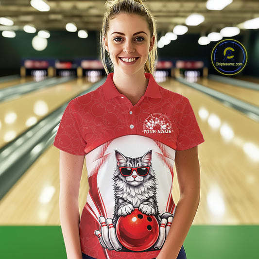 Female model at a bowling lane wearing a bowling polo shirt with a Maine Coon cat in sunglasses beside a bowling ball.