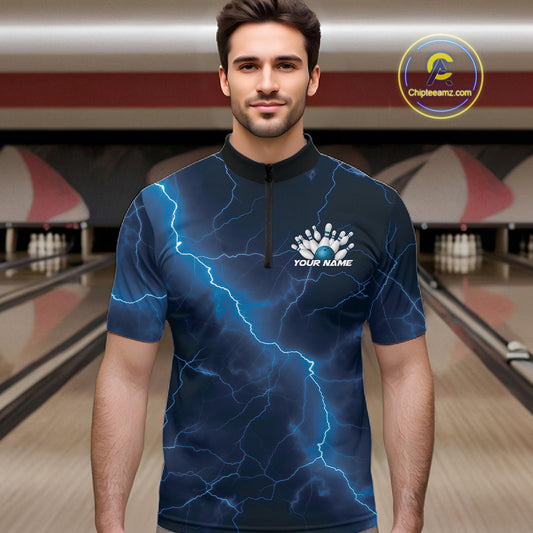 Male model wearing a bowling quarter-zip in a bowling center with blue cobra artwork surrounding a bowling ball and scattered pins.