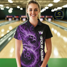 Load image into Gallery viewer, Female model wearing a black bowling polo shirt in a bowling alley featuring a skull clutching a bowling ball surrounded by swirling purple energy flames