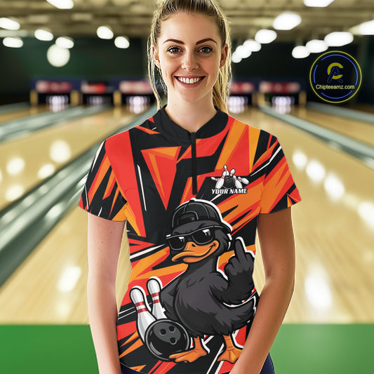 Female model wearing a black and orange bowling quarter-zip at the bowling lane with duck artwork, bowling pins, and geometric accents.