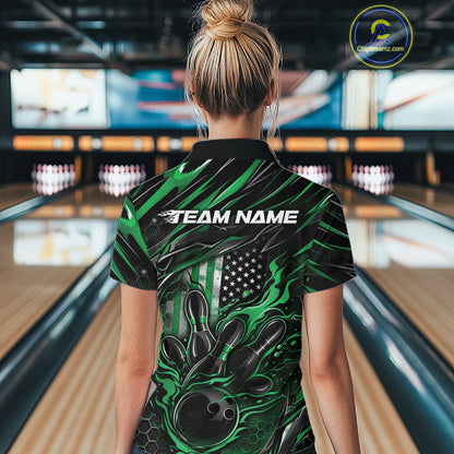Back view of a female model in a bowling alley wearing a black and green polo shirt featuring a flaming bowling ball and patriotic pin artwork.