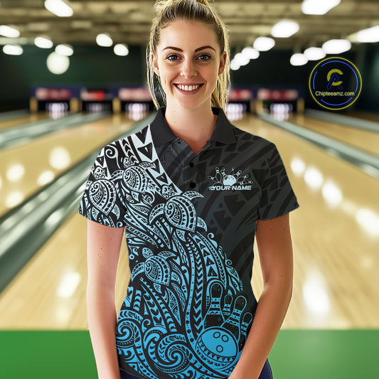 Female model wearing a black and blue bowling polo shirt at the lane with Polynesian-inspired bowling motifs.