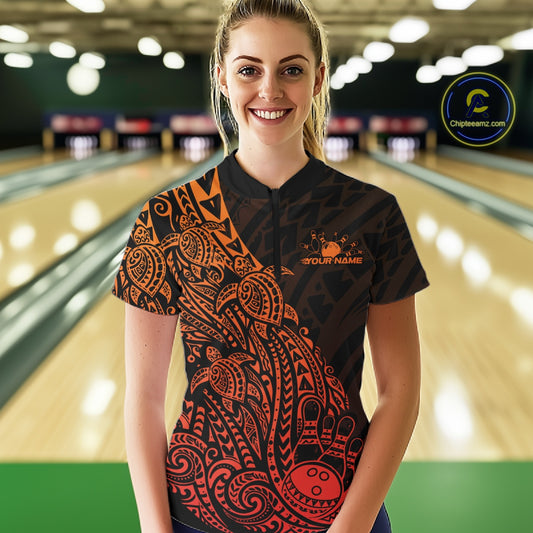 Female model wearing a black and red orange bowling quarter-zip shirt at the lane with tribal swirl bowling graphics.