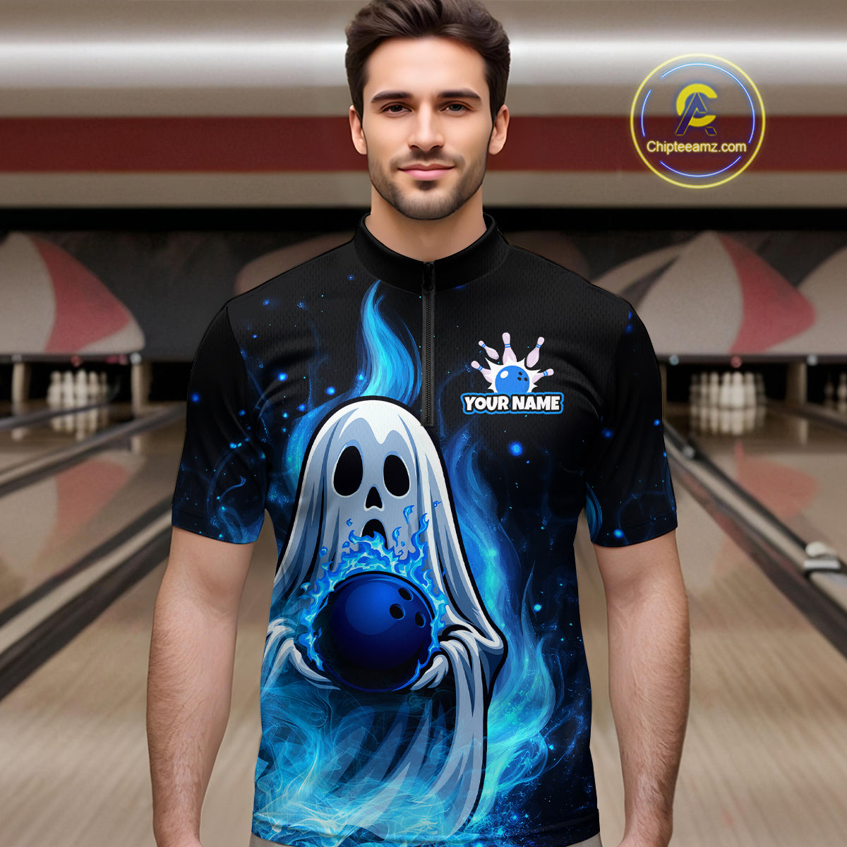 Man wearing a black bowling shirt with a blue ghost and ball design in a bowling alley.